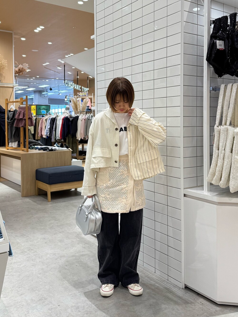 ホワイト系のTシャツ/カットソー、ホワイト系のスカート、ブラック系のデニムパンツを着用したレディースの春コーディネートの3枚目の写真