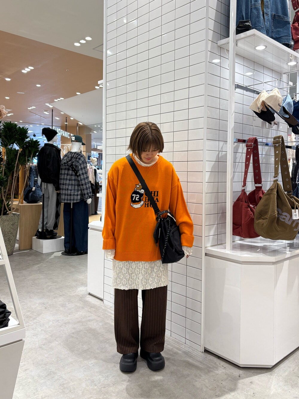 ブラウン系のスラックス、ホワイト系のワンピース、オレンジ系のニット/セーターを着用したレディースの秋コーディネートの2枚目の写真