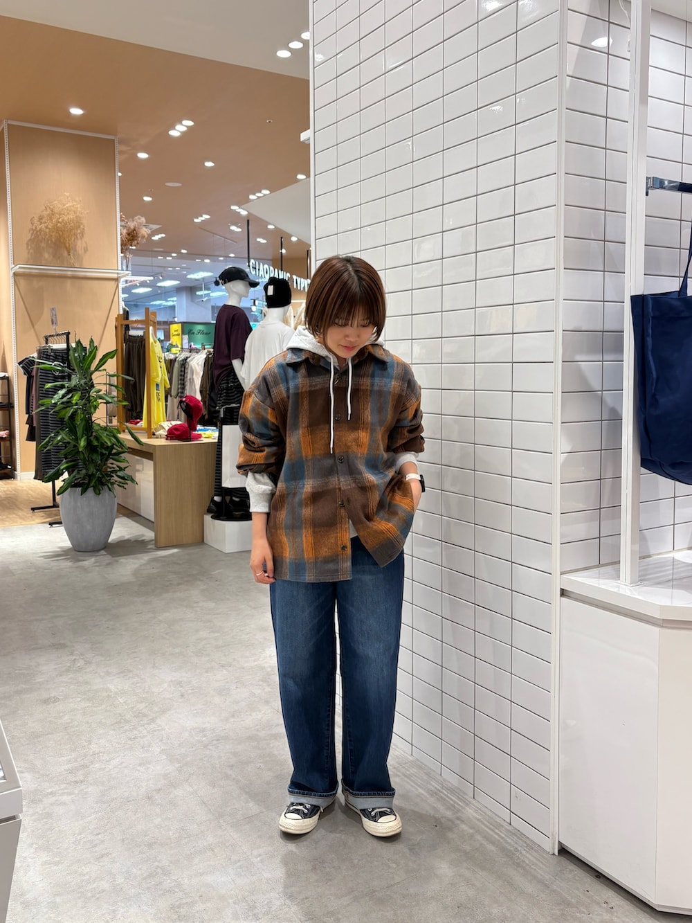 オレンジ系のシャツ/ブラウス、グレー系のパーカー、ブルー系のデニムパンツを着用したレディースの秋コーディネートの2枚目の写真