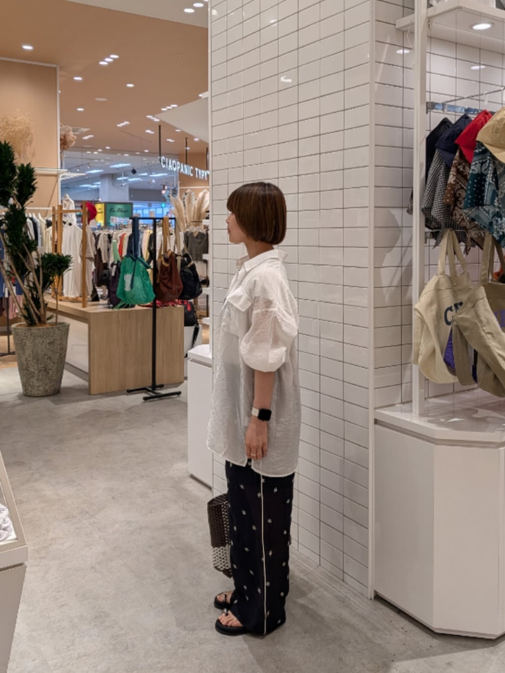 ブラウン系のトートバッグ、ブラック系のその他パンツ、ブラック系のサンダルを着用したレディースの夏コーディネートの3枚目の写真
