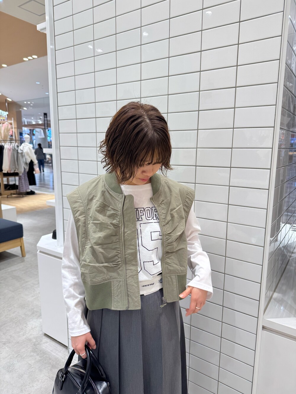 ホワイト系のTシャツ/カットソー、グリーン系のジャケット/アウター、グレー系のスカートを着用したレディースの春コーディネートの4枚目の写真