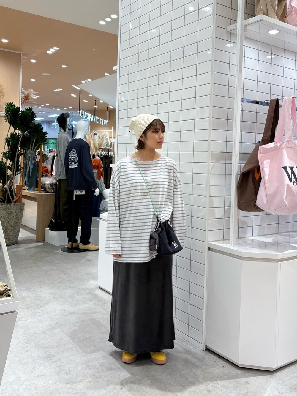 グレー系のTシャツ/カットソー、ブラック系のトートバッグ、グレー系のスカートを着用したレディースの秋コーディネートの2枚目の写真