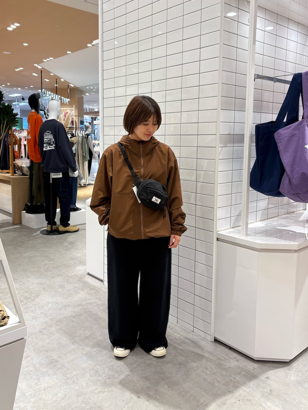 ブラック系のボディバッグ/ウエストポーチ、ブラウン系のマウンテンパーカー、ブラック系のスウェットパンツを着用したレディースの秋コーディネートの2枚目の写真