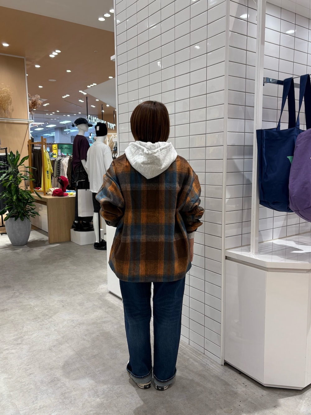 オレンジ系のシャツ/ブラウス、グレー系のパーカー、ブルー系のデニムパンツを着用したレディースの秋コーディネートの4枚目の写真