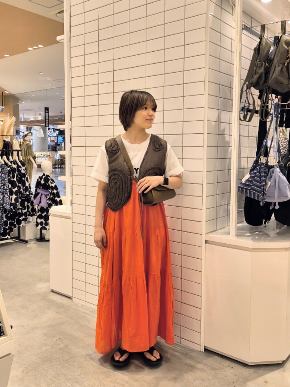 レッド系のワンピース、ホワイト系のTシャツ/カットソー、ブラウン系のショルダーバッグを着用したレディースの夏コーディネートの3枚目の写真