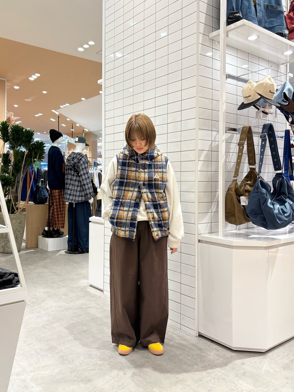 ブラウン系のデニムパンツ、ホワイト系のスウェット、オレンジ系のベストを着用したレディースの秋コーディネートの2枚目の写真