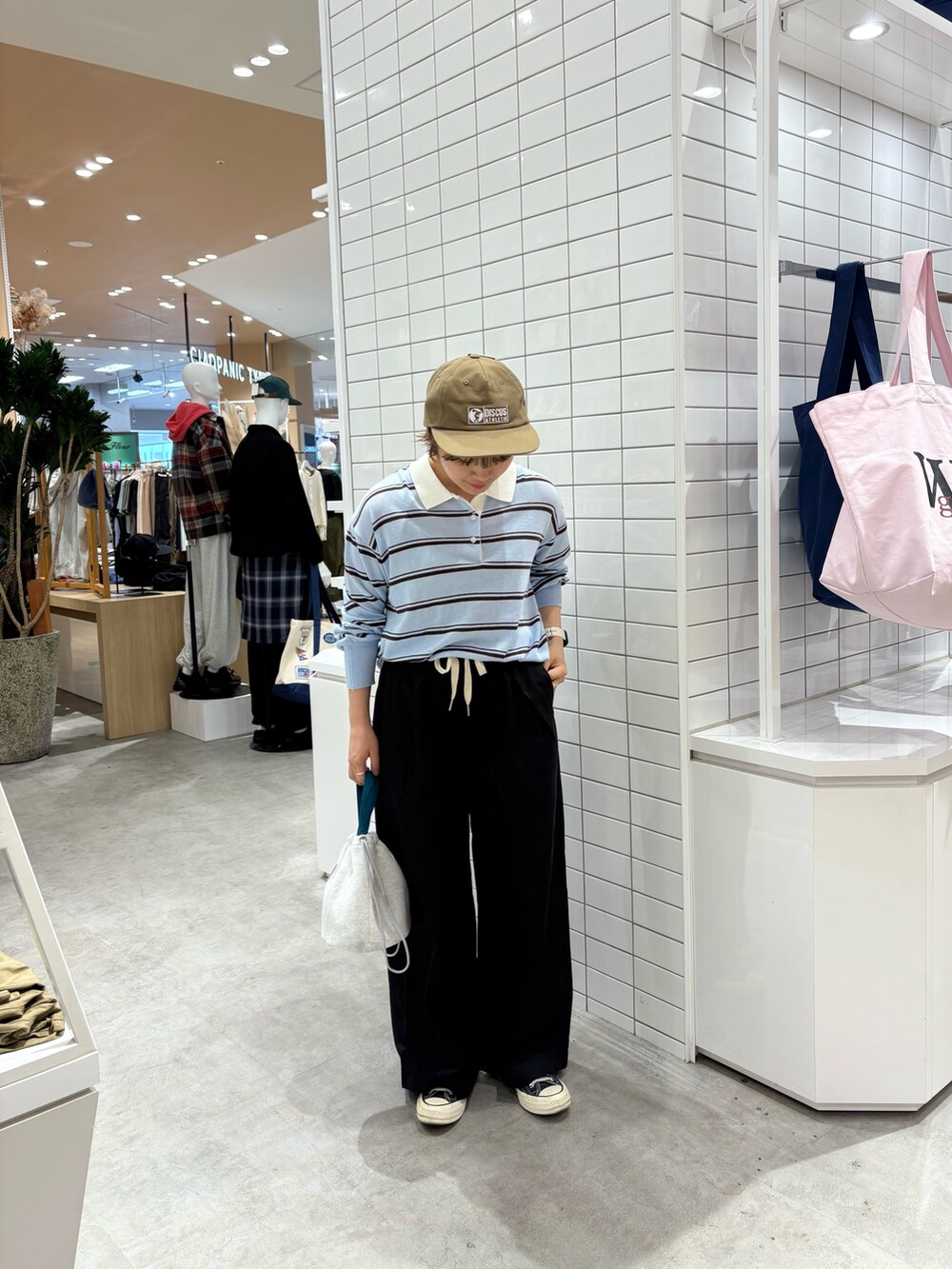 ブルー系のニット/セーター、ブラック系のデニムパンツ、グレー系のハンドバッグを着用したレディースの秋コーディネートの2枚目の写真