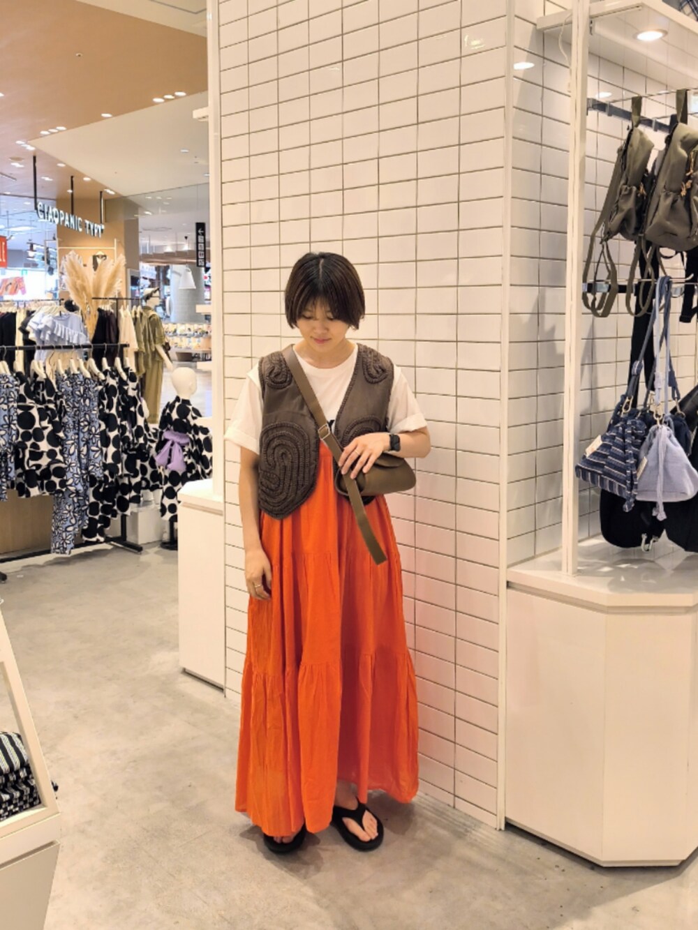 レッド系のワンピース、ホワイト系のTシャツ/カットソー、ブラウン系のショルダーバッグを着用したレディースの夏コーディネートの2枚目の写真