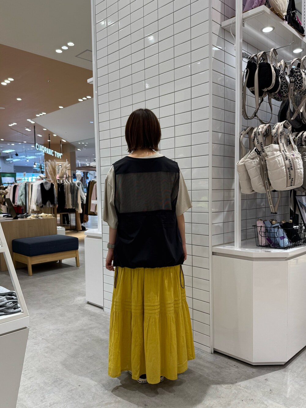 グレー系のTシャツ/カットソー、ブラック系のベスト、イエロー系のスカートを着用したレディースの春コーディネートの4枚目の写真