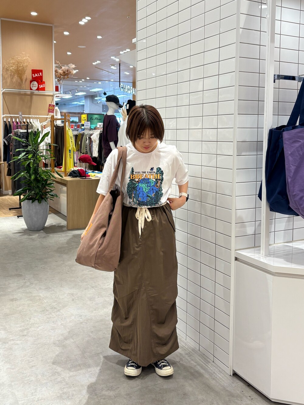 ホワイト系のTシャツ/カットソー、ブラウン系のスカート、ブラウン系のトートバッグを着用したレディースの秋コーディネートの2枚目の写真