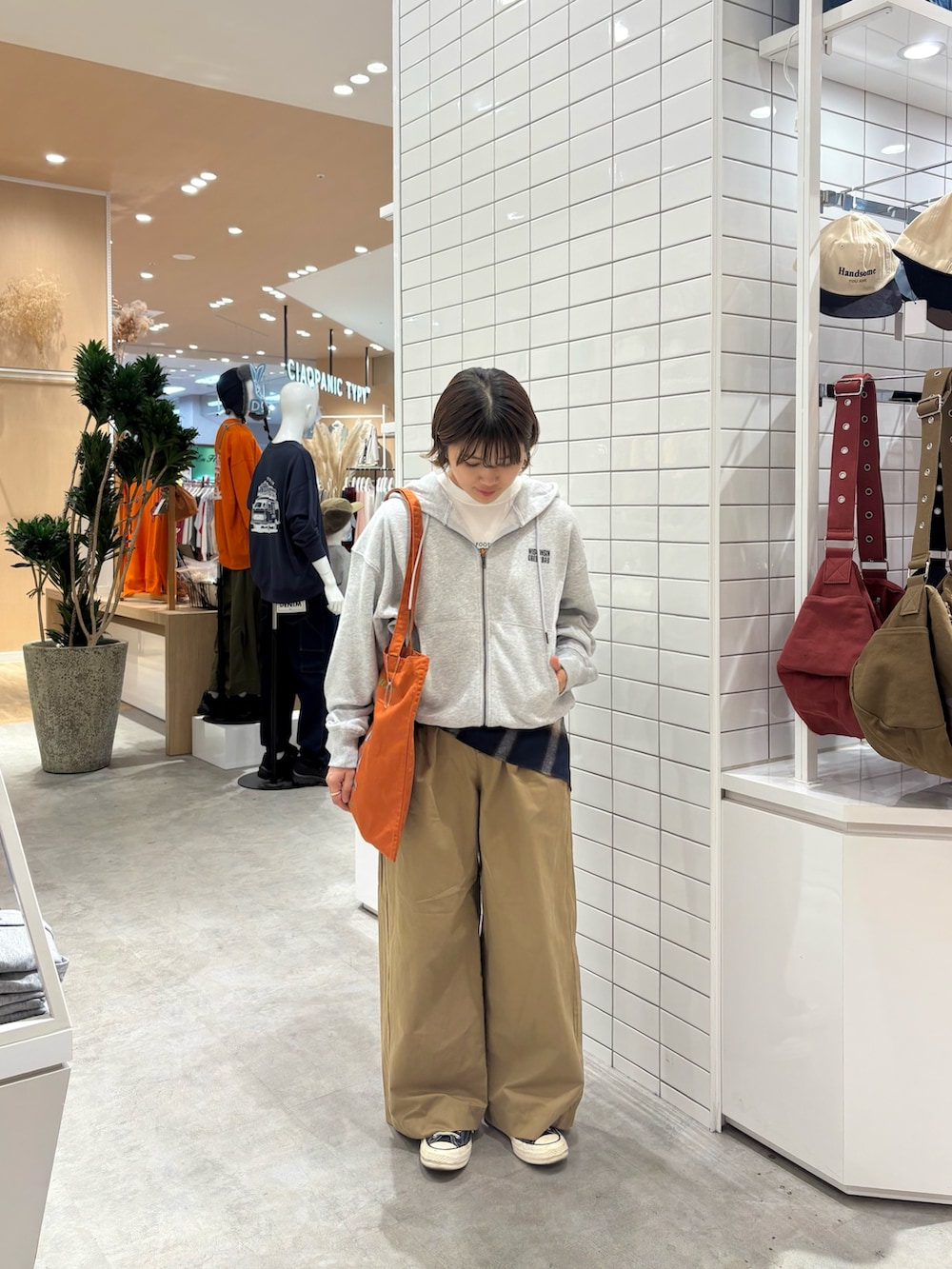 グレー系のパーカー、ベージュ系のデニムパンツ、オレンジ系のトートバッグを着用したレディースの秋コーディネートの2枚目の写真