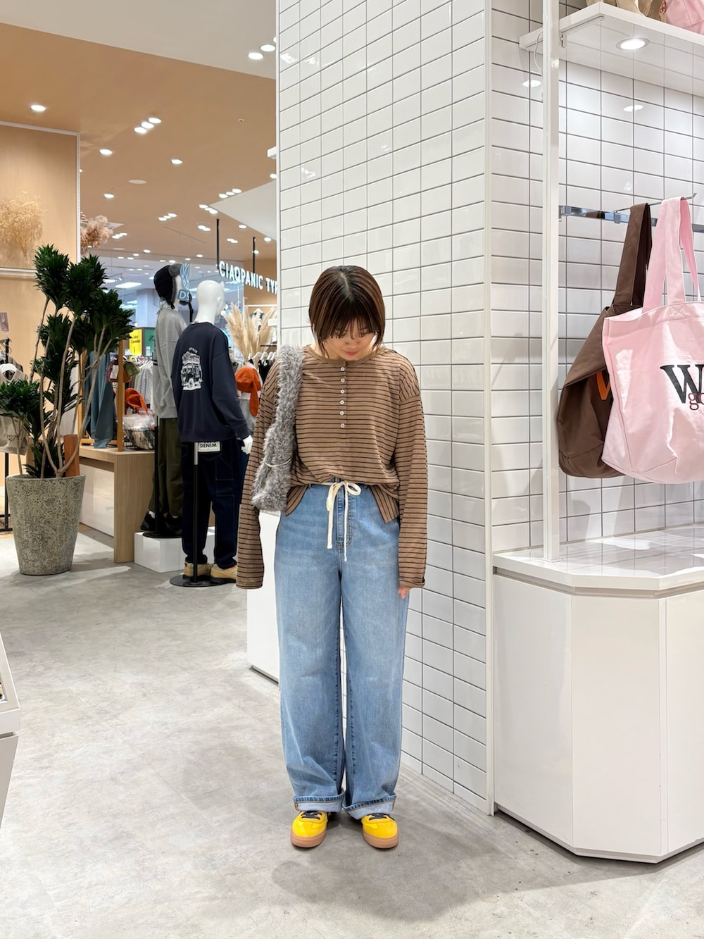 ブラウン系のTシャツ/カットソー、ブルー系のデニムパンツ、グレー系のトートバッグを着用したレディースの秋コーディネートの2枚目の写真