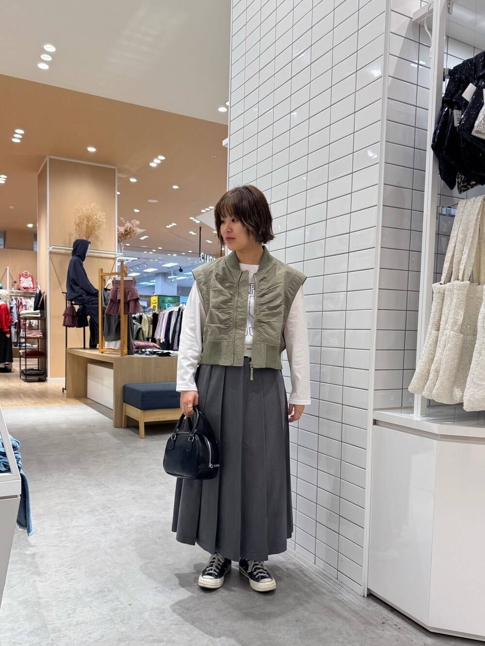 ホワイト系のTシャツ/カットソー、グリーン系のジャケット/アウター、グレー系のスカートを着用したレディースの春コーディネートの2枚目の写真