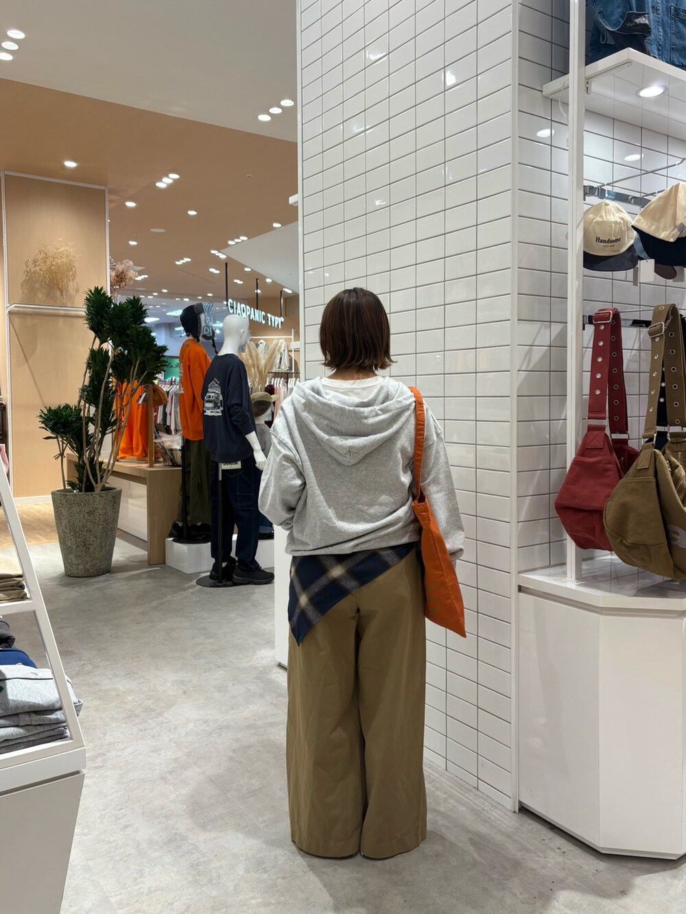 グレー系のパーカー、ベージュ系のデニムパンツ、オレンジ系のトートバッグを着用したレディースの秋コーディネートの4枚目の写真