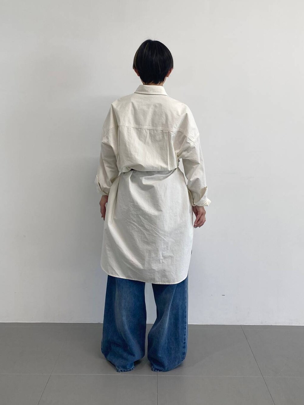ブルー系のデニムパンツ、ホワイト系のシャツワンピース、ブラック系のベルトを着用したレディースの冬コーディネートの3枚目の写真