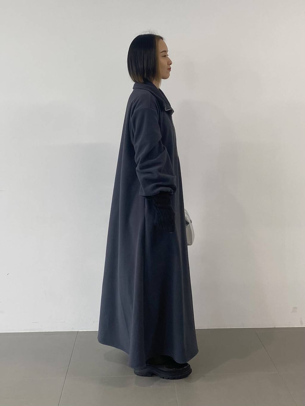 シルバー系のショルダーバッグ、ブラック系のブーツ、グレー系のワンピースを着用したレディースの秋コーディネートの4枚目の写真