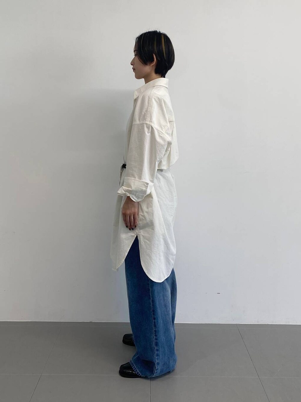 ブルー系のデニムパンツ、ホワイト系のシャツワンピース、ブラック系のベルトを着用したレディースの冬コーディネートの4枚目の写真