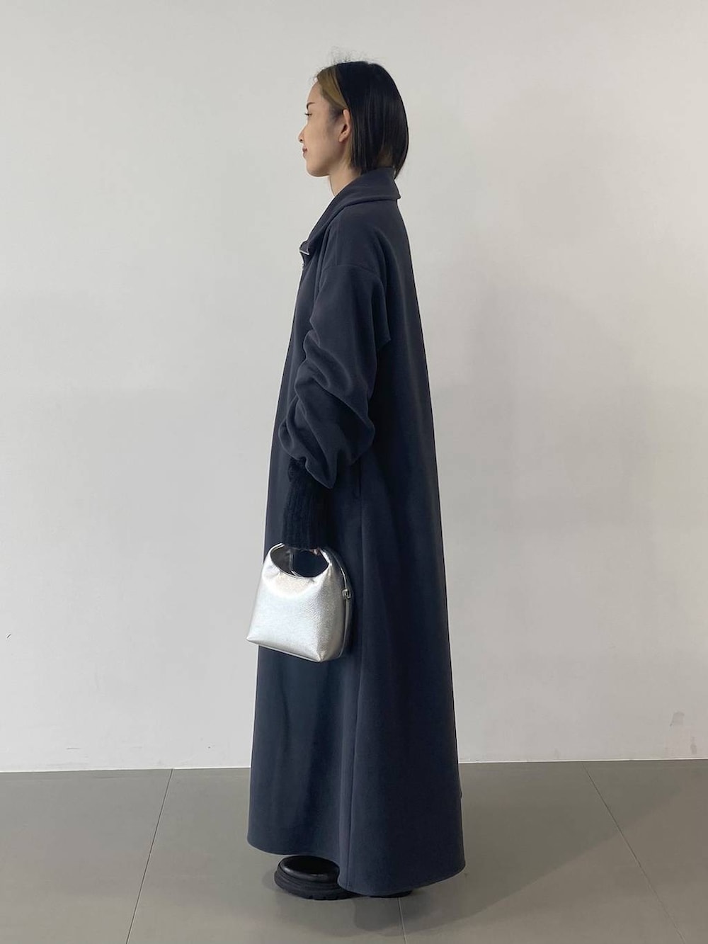 シルバー系のショルダーバッグ、ブラック系のブーツ、グレー系のワンピースを着用したレディースの秋コーディネートの2枚目の写真