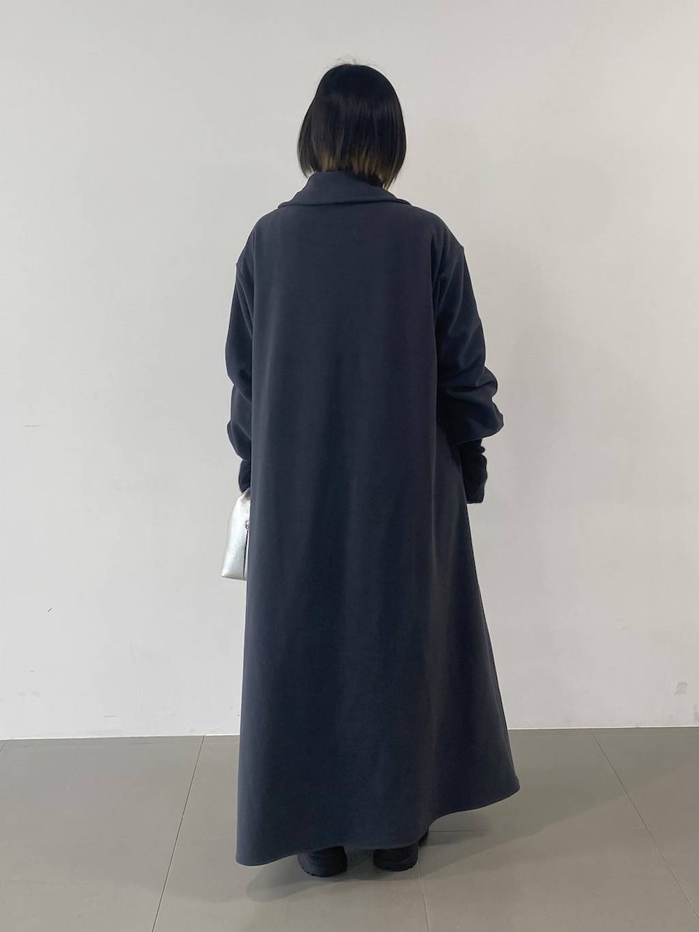 シルバー系のショルダーバッグ、ブラック系のブーツ、グレー系のワンピースを着用したレディースの秋コーディネートの3枚目の写真