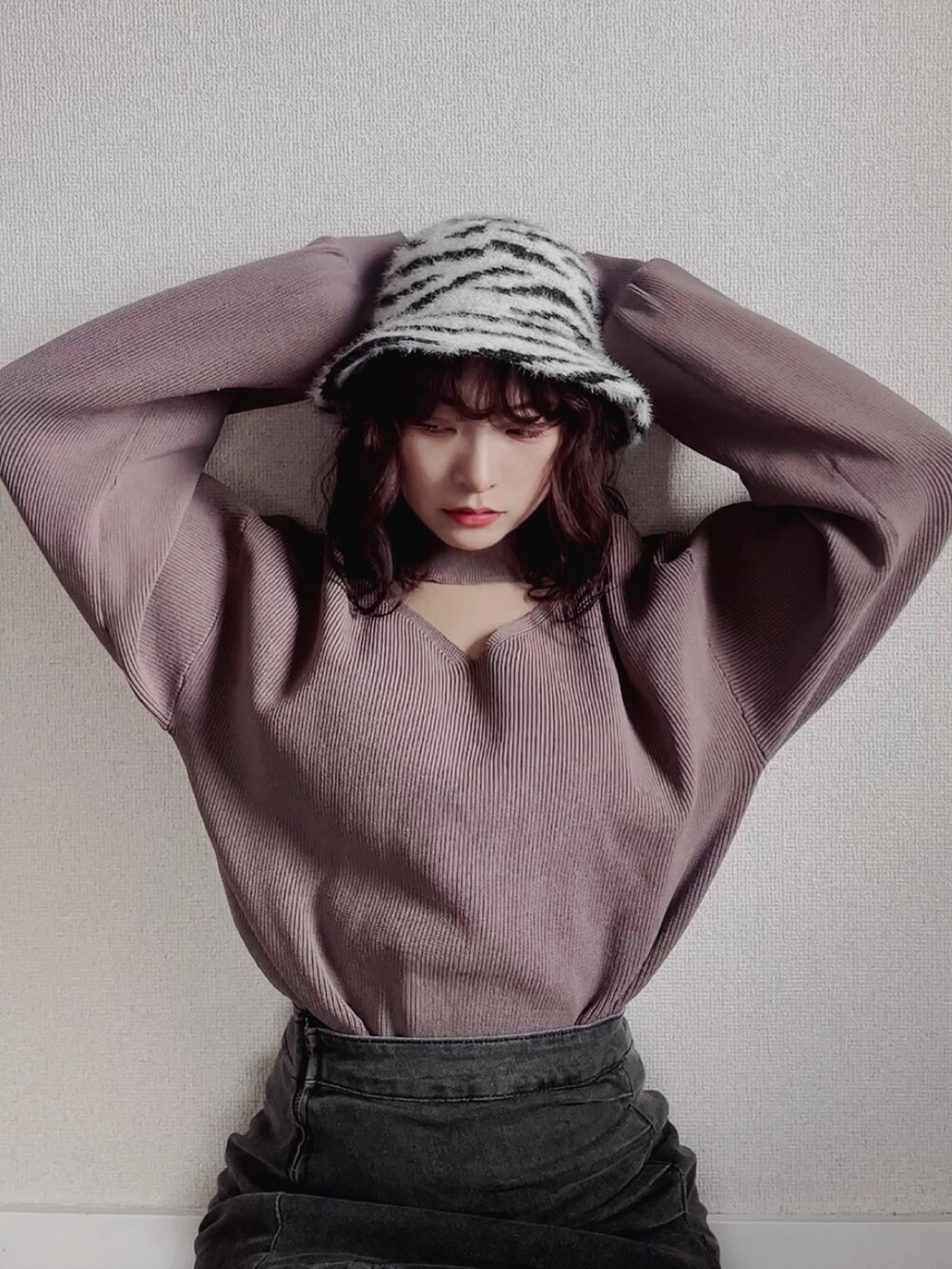 グレー系のデニムスカート、ブラウン系のニット/セーター、ブラック系のハットを着用したレディースの秋コーディネートの2枚目の写真