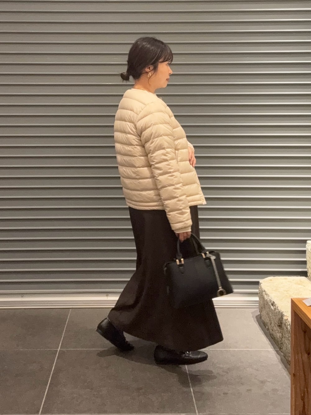 ホワイト系のダウンジャケット/コート、ブラウン系のスカート、ブラック系のパンプスを着用したレディースの秋コーディネートの2枚目の写真
