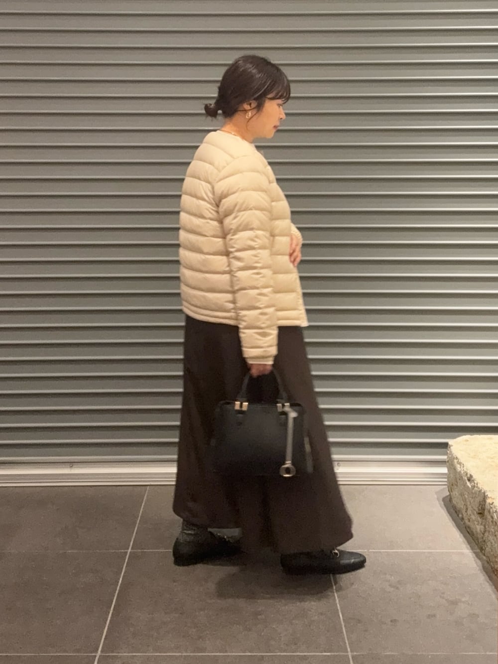 ホワイト系のダウンジャケット/コート、ブラウン系のスカート、ブラック系のパンプスを着用したレディースの秋コーディネートの3枚目の写真