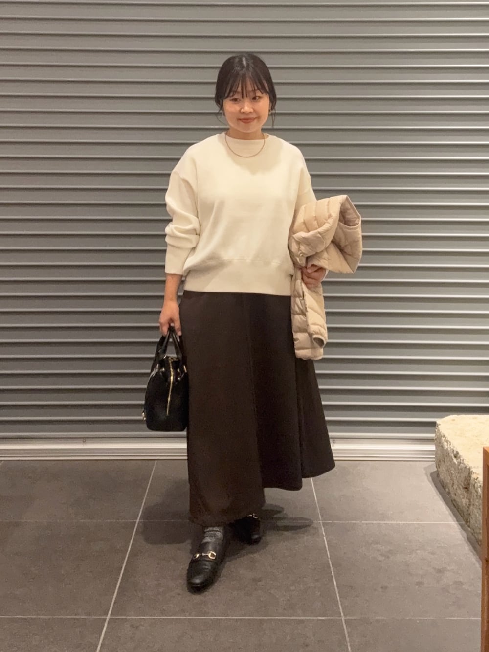 ホワイト系のダウンジャケット/コート、ブラウン系のスカート、ブラック系のパンプスを着用したレディースの秋コーディネートの4枚目の写真