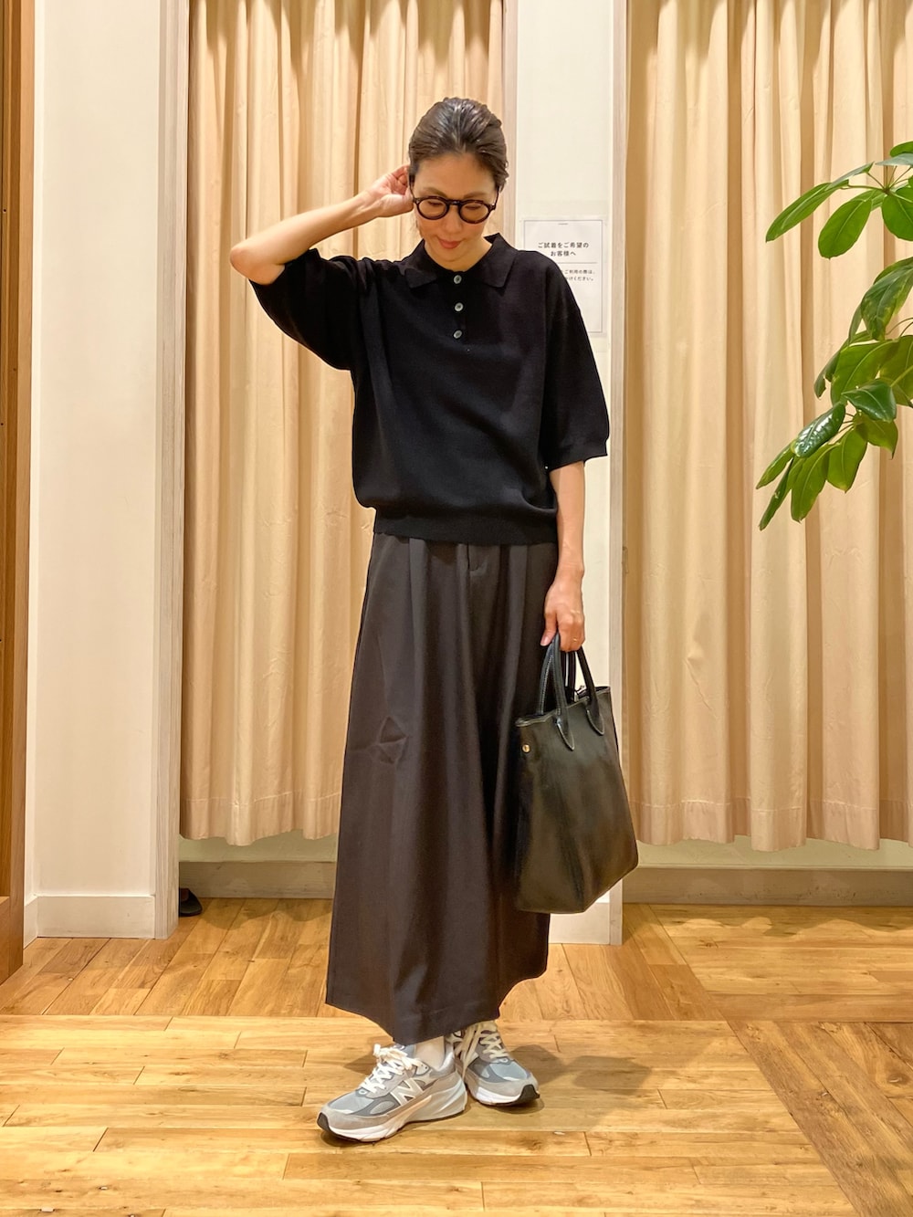 ブラック系のポロシャツ、グレー系のスカート、ブラック系のトートバッグを着用したレディースの秋コーディネートの2枚目の写真