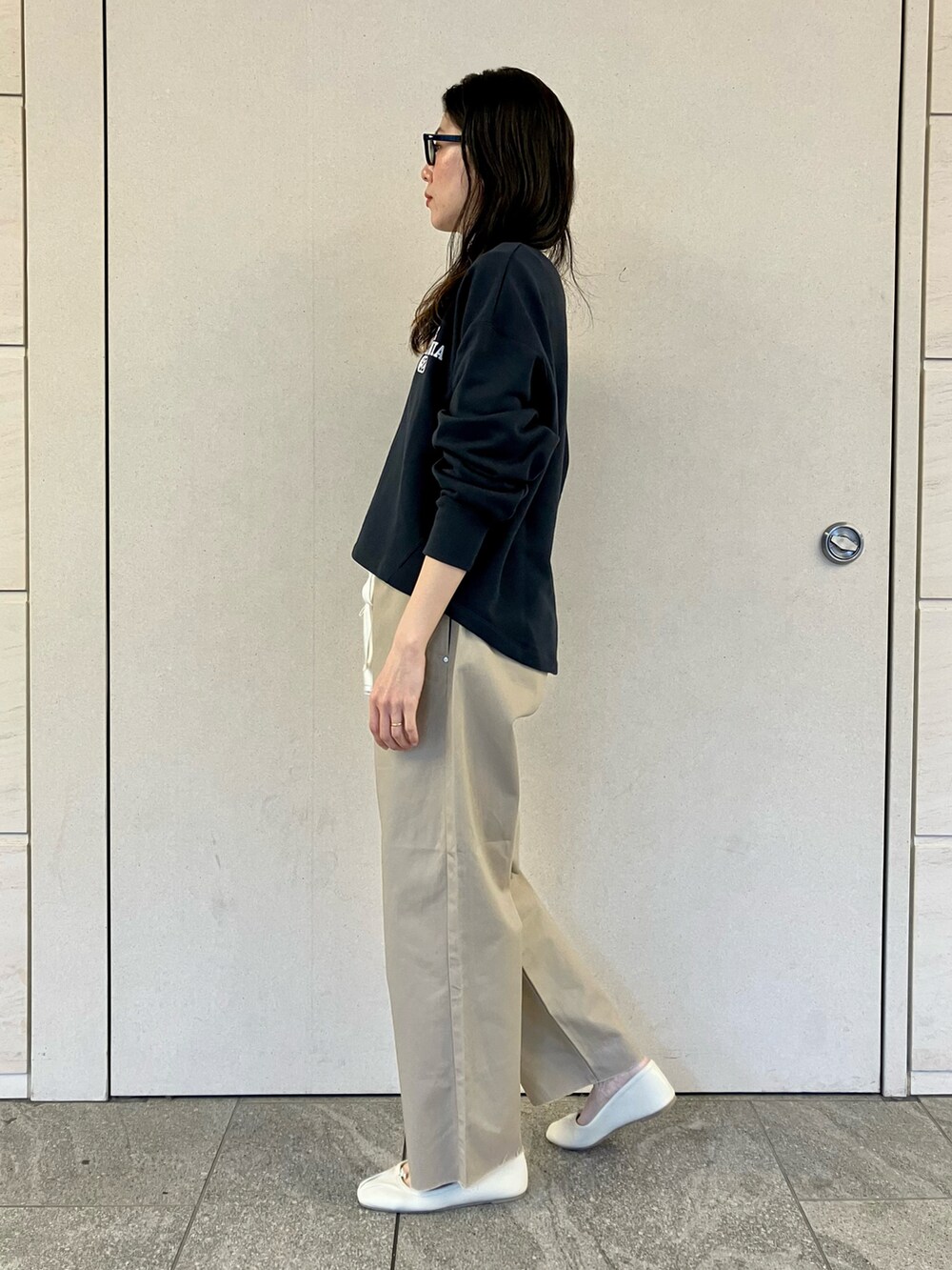 ブルー系のスウェット、ベージュ系のチノパンツ、ホワイト系のバレエシューズを着用したレディースの春コーディネートの3枚目の写真