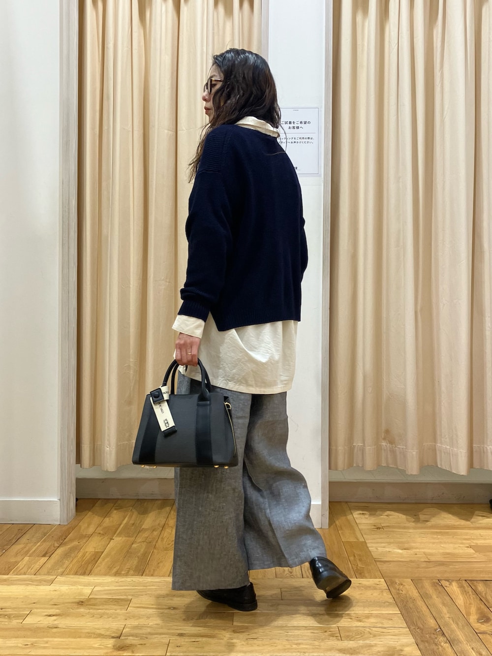 ブルー系のニット/セーター、ホワイト系のシャツ/ブラウス、グレー系のその他パンツを着用したレディースの春コーディネートの2枚目の写真