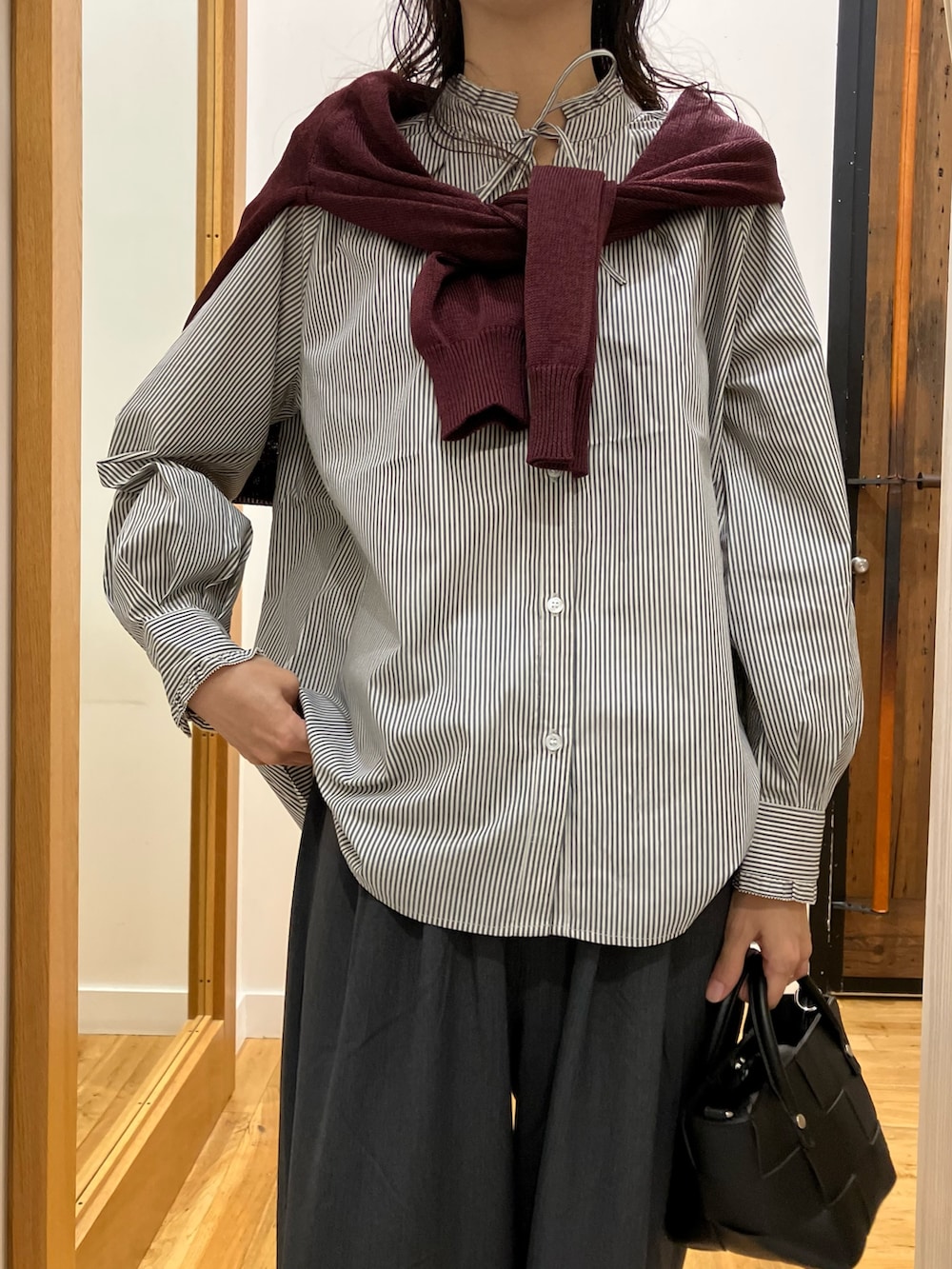 ブラック系のシャツ/ブラウス、レッド系のカーディガン/ボレロ、ブラック系のハンドバッグを着用したレディースの秋コーディネートの4枚目の写真