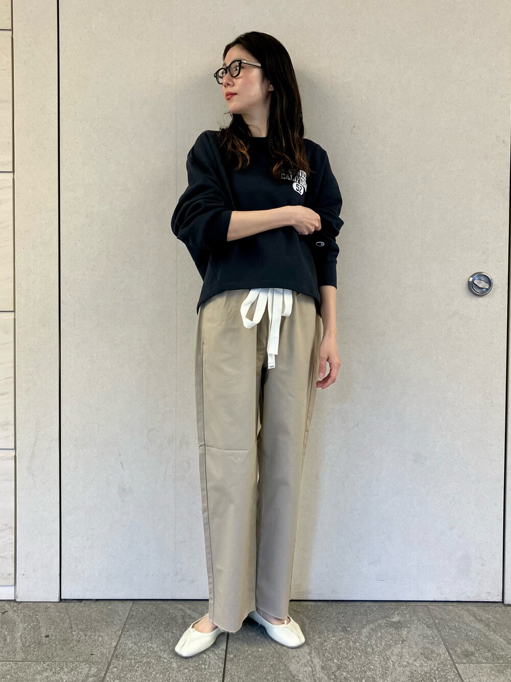 ブルー系のスウェット、ベージュ系のチノパンツ、ホワイト系のバレエシューズを着用したレディースの春コーディネートの2枚目の写真