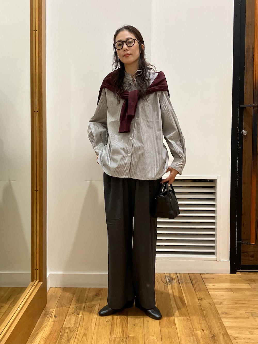 ブラック系のシャツ/ブラウス、レッド系のカーディガン/ボレロ、ブラック系のハンドバッグを着用したレディースの秋コーディネートの2枚目の写真