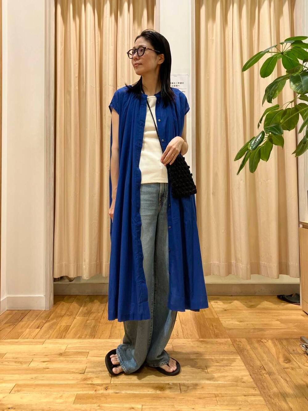 ブルー系のデニムパンツ、ブラック系のサンダル、ホワイト系のタンクトップを着用したレディースの夏コーディネートの2枚目の写真