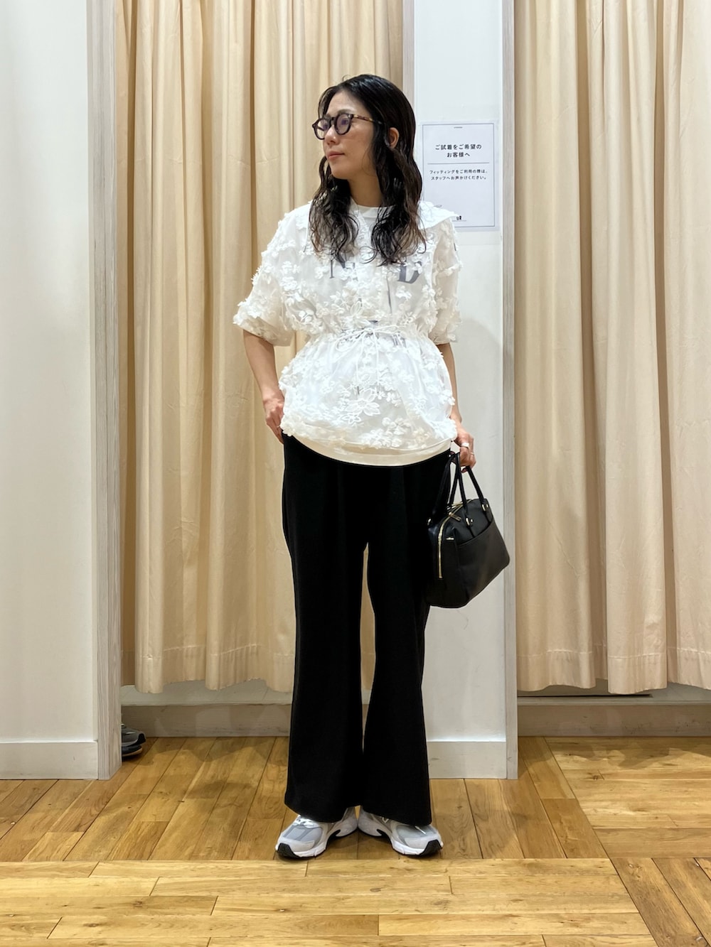 ホワイト系のパーカー、グレー系のスニーカー、ブラック系のその他パンツを着用したレディースの春コーディネートの2枚目の写真