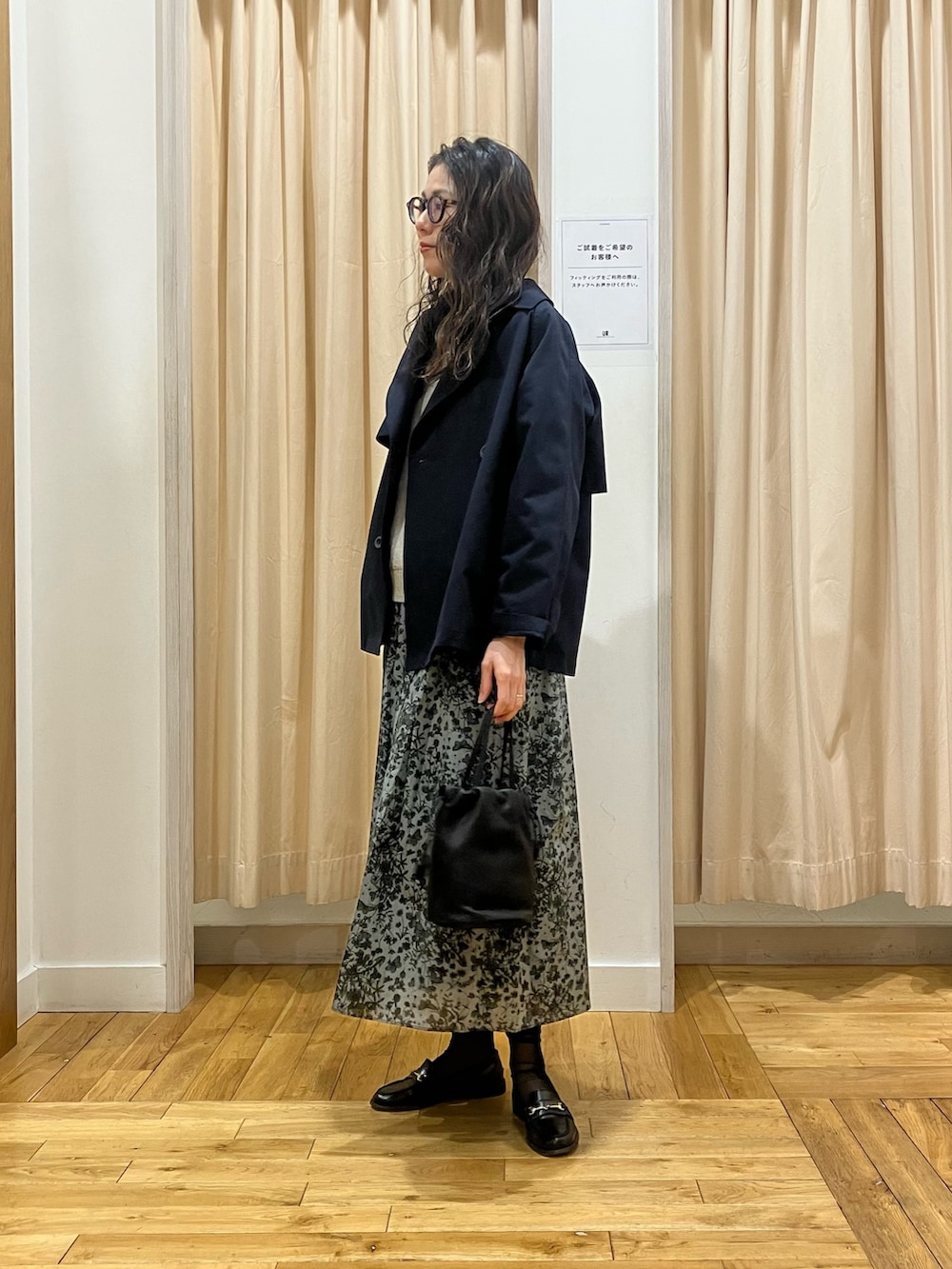 ブラック系のスカート、ブルー系のトレンチコート、グレー系のニット/セーターを着用したレディースの春コーディネートの2枚目の写真