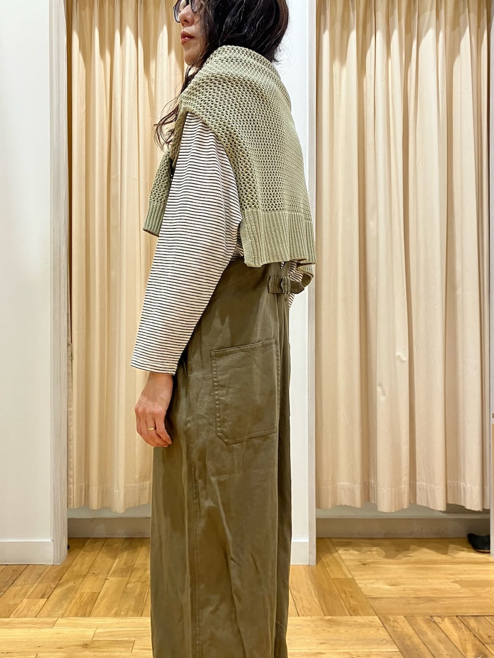 グリーン系のサロペット/オーバーオール、ベージュ系のTシャツ/カットソー、グリーン系のニット/セーターを着用したレディースの春コーディネートの4枚目の写真