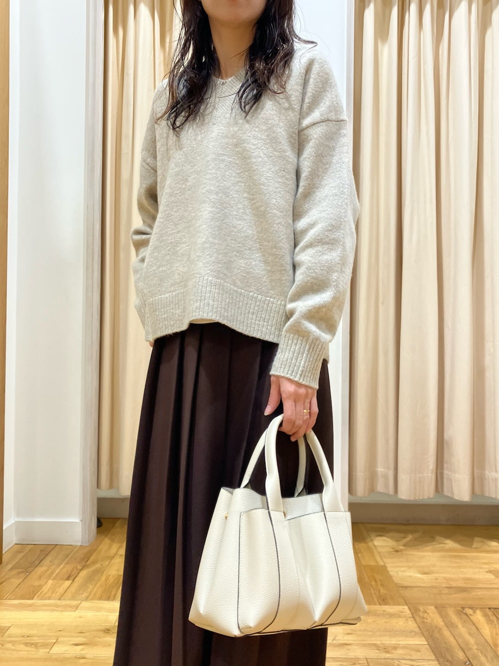 ベージュ系のニット/セーター、ブラウン系のスカート、ホワイト系のトートバッグを着用したレディースの冬コーディネートの4枚目の写真