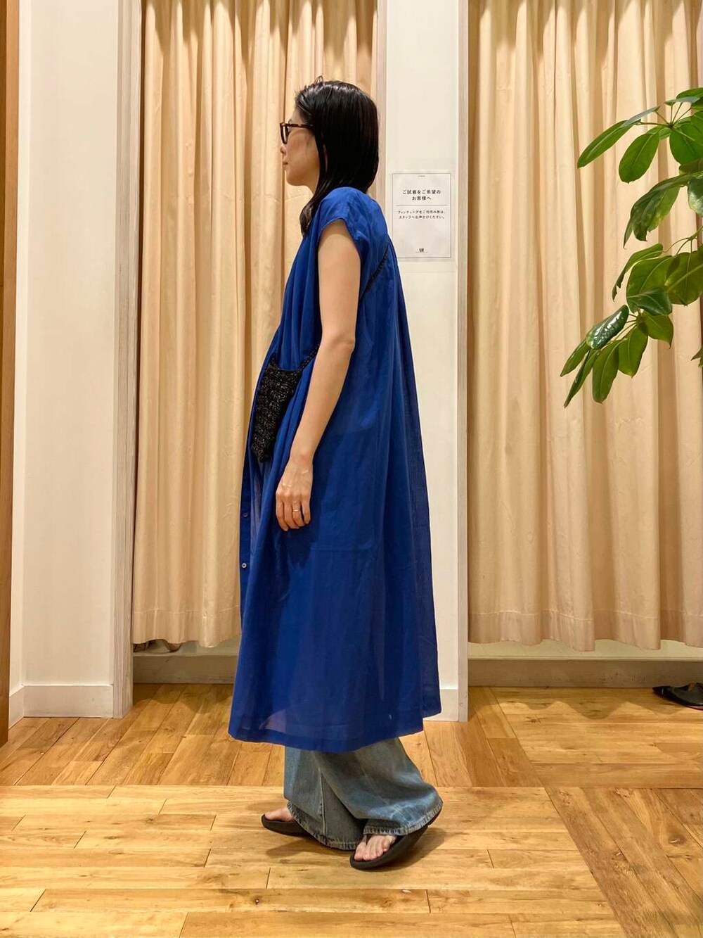 ブルー系のデニムパンツ、ブラック系のサンダル、ホワイト系のタンクトップを着用したレディースの夏コーディネートの3枚目の写真