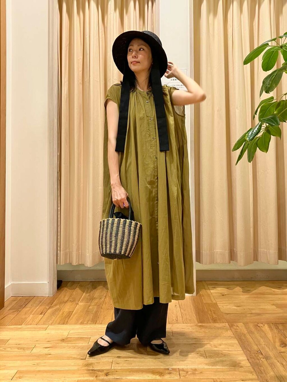 ブラック系のハンドバッグ、ブルー系のその他パンツ、グリーン系のワンピースを着用したレディースの夏コーディネートの2枚目の写真