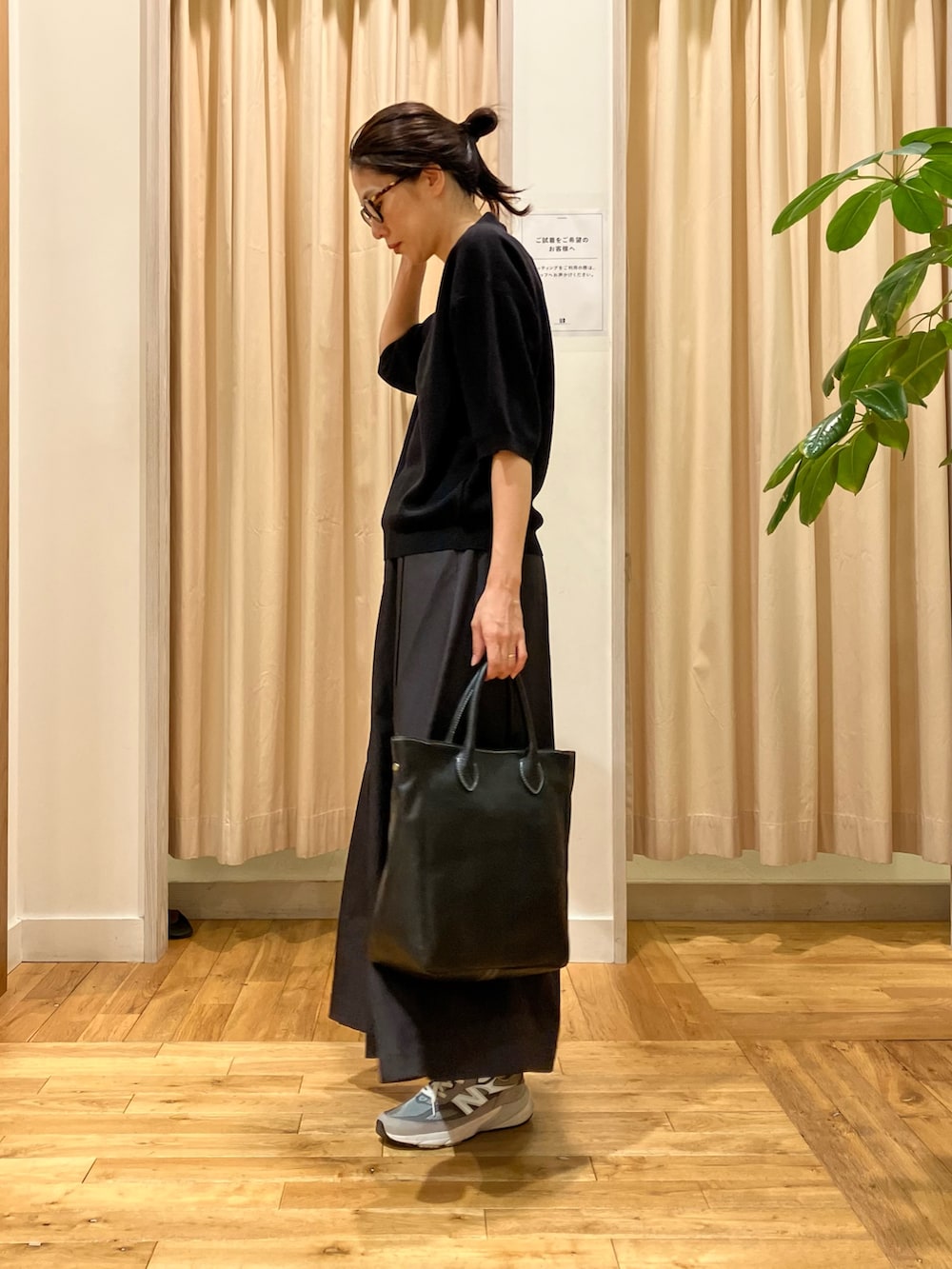 ブラック系のポロシャツ、グレー系のスカート、ブラック系のトートバッグを着用したレディースの秋コーディネートの3枚目の写真