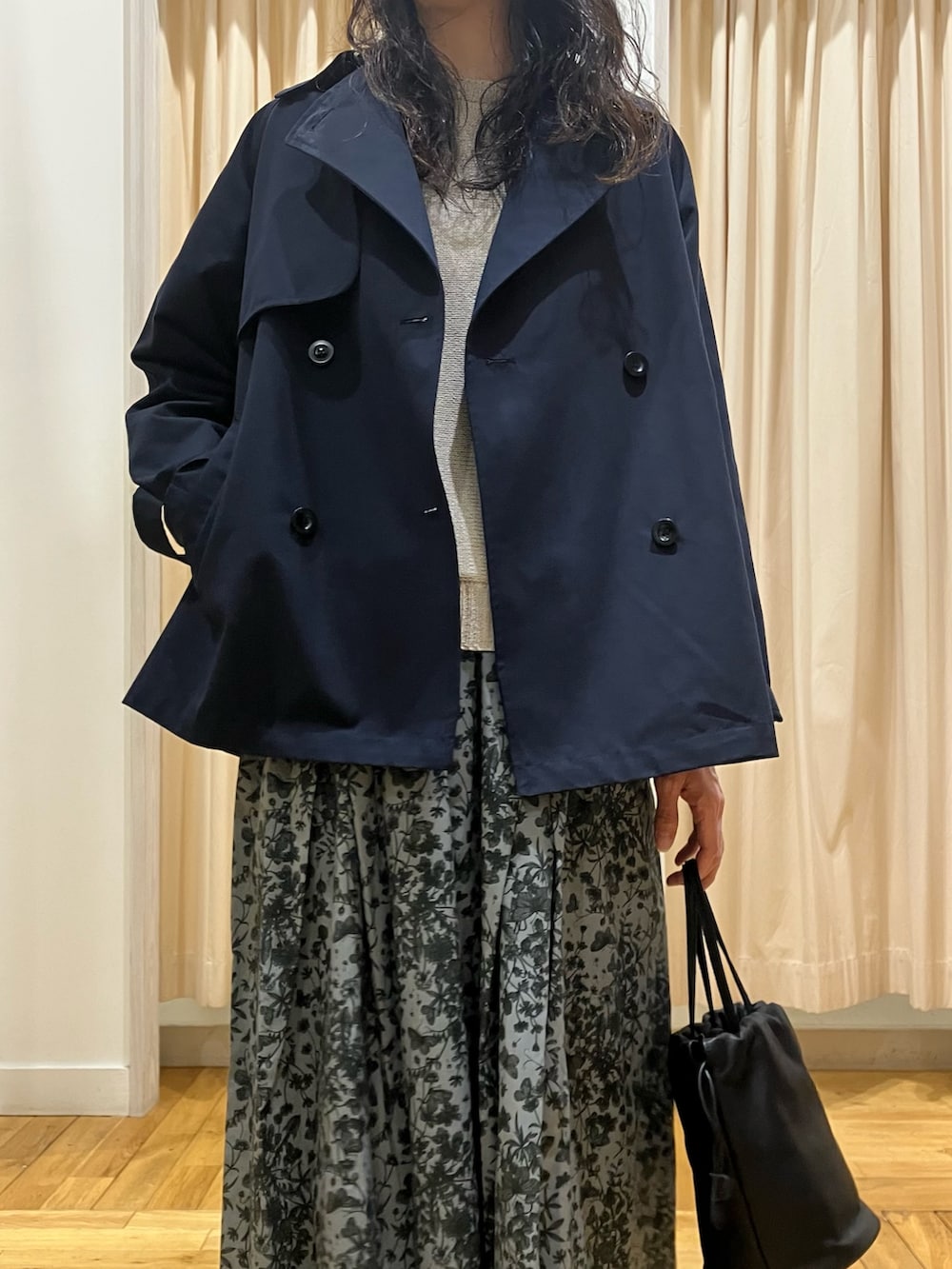 ブラック系のスカート、ブルー系のトレンチコート、グレー系のニット/セーターを着用したレディースの春コーディネートの4枚目の写真