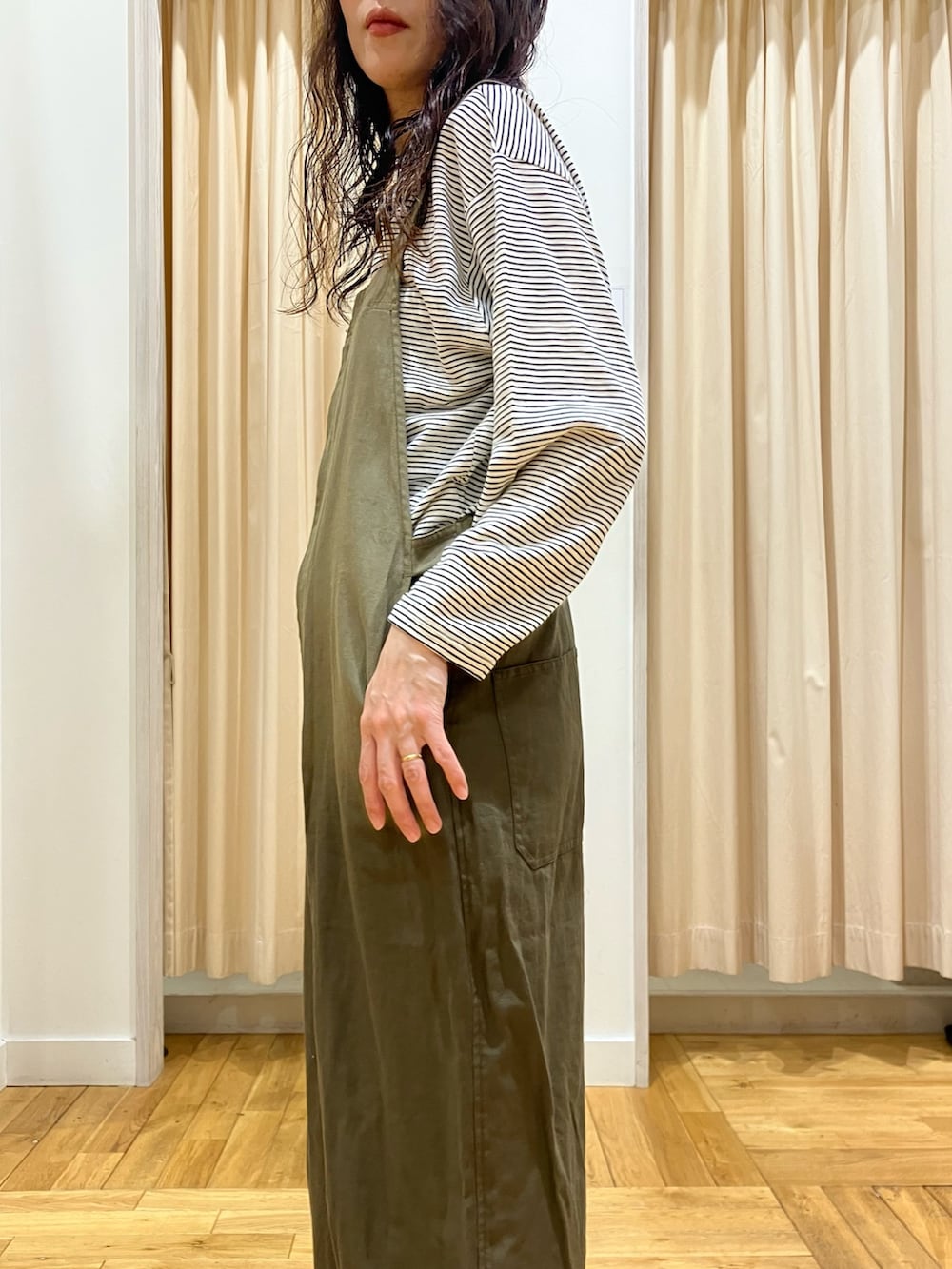 グリーン系のサロペット/オーバーオール、ベージュ系のTシャツ/カットソー、グリーン系のニット/セーターを着用したレディースの春コーディネートの6枚目の写真