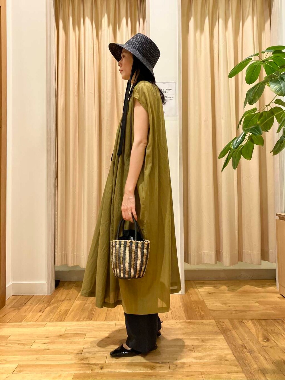 ブラック系のハンドバッグ、ブルー系のその他パンツ、グリーン系のワンピースを着用したレディースの夏コーディネートの3枚目の写真