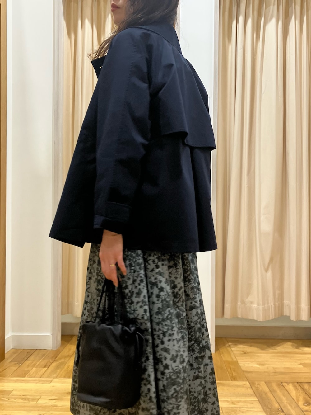 ブラック系のスカート、ブルー系のトレンチコート、グレー系のニット/セーターを着用したレディースの春コーディネートの5枚目の写真