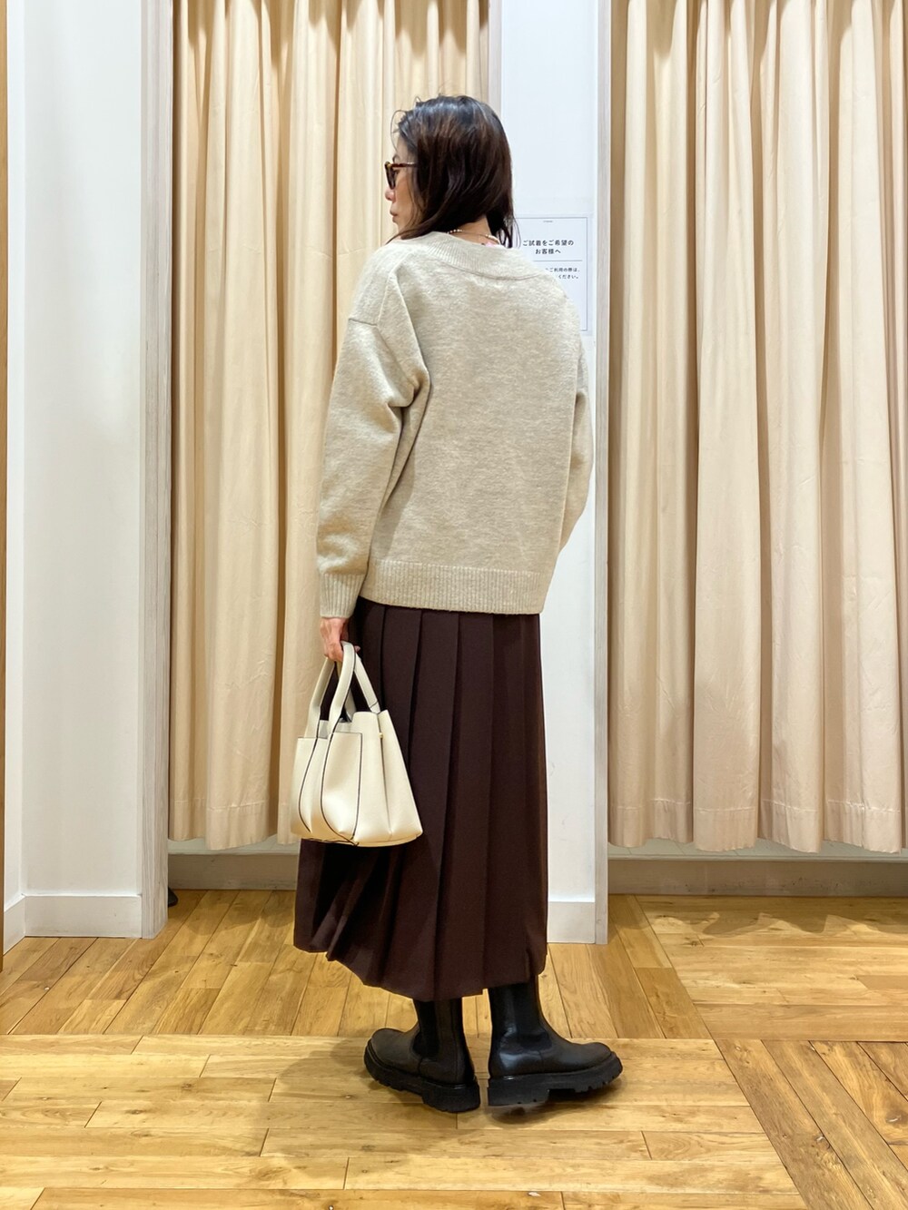 ベージュ系のニット/セーター、ブラウン系のスカート、ホワイト系のトートバッグを着用したレディースの冬コーディネートの3枚目の写真