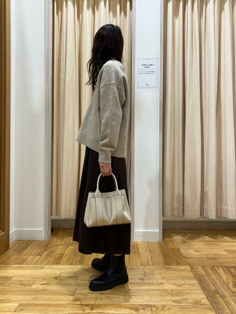ベージュ系のニット/セーター、ブラウン系のスカート、ホワイト系のトートバッグを着用したレディースの冬コーディネートの2枚目の写真