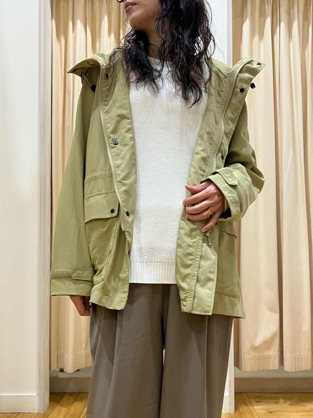 ホワイト系のニット/セーター、グリーン系のマウンテンパーカー、グレー系のその他パンツを着用したレディースの春コーディネートの4枚目の写真