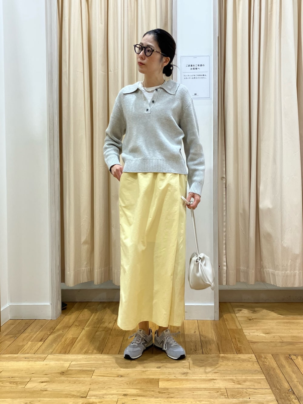 グレー系のニット/セーター、イエロー系のスカート、グレー系のスニーカーを着用したレディースの冬コーディネートの2枚目の写真