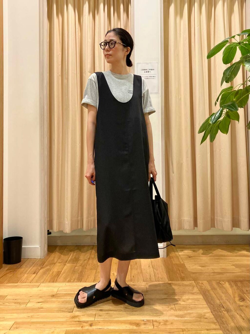 ブラック系のショルダーバッグ、ブラック系のサンダル、グレー系のTシャツ/カットソーを着用したレディースの夏コーディネートの2枚目の写真